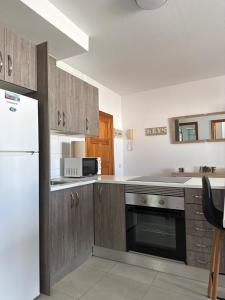 una cucina con mobili in legno e un frigorifero bianco di Casa Lucia 2 a Cotillo