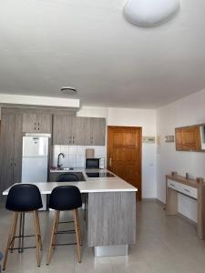 una cucina con bancone e 2 sgabelli da bar di Casa Lucia 2 a Cotillo Altre 11 foto