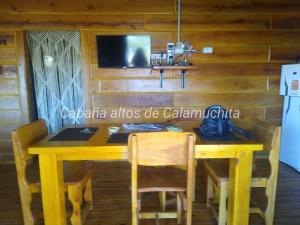 a wooden table with chairs and a tv on a wall at Cabaña Altos de Calamuchita in Santa Rosa de Calamuchita