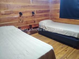 two twin beds in a room with wooden walls at Cabaña Altos de Calamuchita in Santa Rosa de Calamuchita