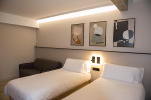 una stanza d'albergo con due letti e una sedia di TUEH TUDELA BALCON DE BARDENAS a Tudela