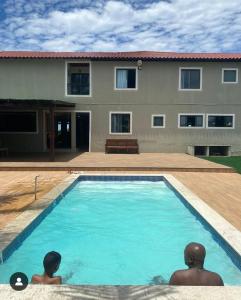 two men sitting in a swimming pool in front of a house at Pousada Altas Ondas in Saquarema +4 photos