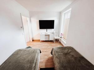 a white room with two beds and a flat screen tv at Ferienwohnung Sommerwind in Börgerende-Rethwisch