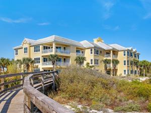 a large yellow house on the beach with a wooden boardwalk at 305 West in Gulf Highlands