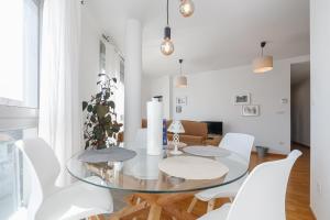 a dining room with a glass table and white chairs at Con parking y vistas al mar by CABANA Rentals in A Guarda