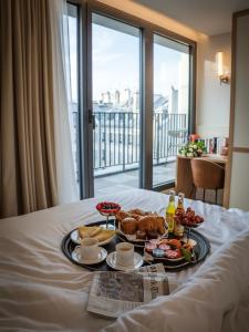 a tray of food on a bed in a hotel room at Quartier Libre Opera in Paris