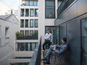 two men sitting on the balcony of a building at Quartier Libre Opera in Paris