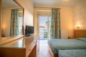 a bedroom with a bed and a tv and a mirror at Plaza Hotel in Zakynthos