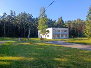 a white building in the middle of a park at Vormsi Ohvitseride Maja korter nr 4 in Hullo