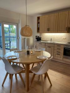 a kitchen with a wooden table and white chairs at HEIDEmarie in Walle