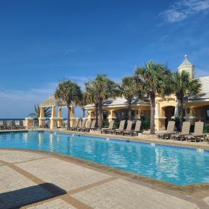 un complejo con piscina con palmeras y sillas en Sand Castle, en Gulf Highlands