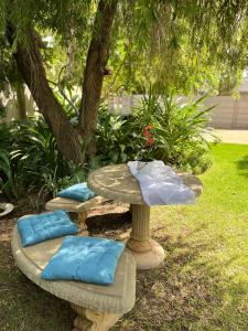 two benches with pillows and a table in a yard at Tanya's Haven Guesthouse in Klerksdorp
