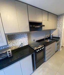 a kitchen with white cabinets and black counter tops at 2 quartos São Conrado ao lado Hotel Nacional in Rio de Janeiro