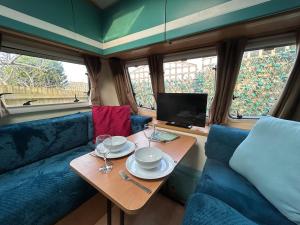 a table with plates and wine glasses on a train at The Rural Cosy Camper by MaisonPro in Stroud