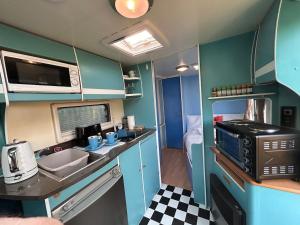 a small kitchen with a sink and a microwave at The Rural Cosy Camper by MaisonPro in Stroud