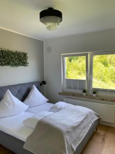 a bedroom with a bed with white sheets and two windows at #2 Ommi Kese Sansibar Apartment Panorama Balkon in Olpe