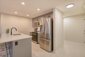 Una cocina con refrigerador y gabinetes de acero inoxidable. en Stylish & Comfy Mountain Escape King Bed PS5!, en Calgary