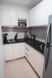 una cucina con mobili bianchi e un piano di lavoro nero di Modern Tropical Luxe Apartment - Boracay Newcoast a Boracay Altre 30 foto