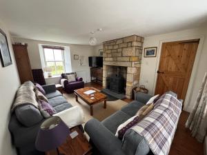 a living room with a couch and a fireplace at Charming cottage with loch and hill views nr Edinburgh in Cobbinshaw
