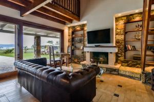 a living room with a leather couch and a fireplace at OpenSea Villa in Thermisía
