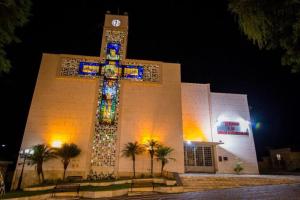 eine Kirche mit einem Kreuz vor einem Gebäude in der Unterkunft Recanto da Nicea in Córrego do Bom Jesus + 26 Fotos