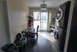 lavadero con lavadora y mesa con sillas en Home Inn Calgary Dalhousie, en Calgary