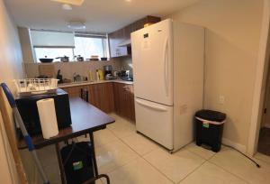 Una cocina con un refrigerador blanco y una mesa. en Home Inn Calgary Dalhousie, en Calgary
