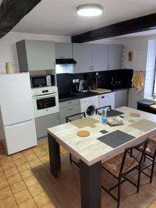 a kitchen with a table and white appliances at L'échappée Verte Ambiance Nature in Deville