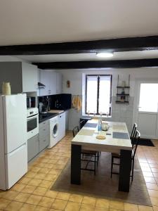 a kitchen with a table and a white refrigerator at L'échappée Verte Ambiance Nature in Deville