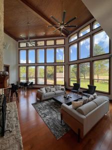 a large living room with a ceiling fan and large windows at 22-Acres Mansion - Pool Party Venue Games & More in Garland