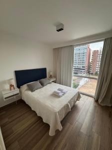 a bedroom with a bed and a large window at Departamento céntrico con cochera y piscina Paz 341 in Tandil +6 photos