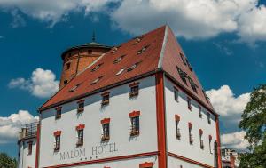 a white building with a red roof and a tower at Malom Hotel in Debrecen