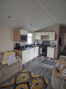 a living room with a couch and a kitchen at 3 bedroom Caravan Craigtara in Ayr
