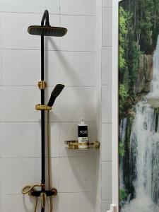 een douche in een badkamer met een watervalschilderij aan de muur bij فندق وادي السحتن in Al Ambaḩ