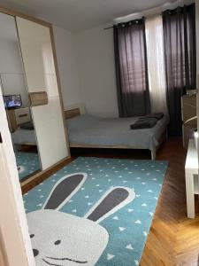 a room with a bed and a rug with a rabbit on it at JOVAN APARTMAN in Rospi Ćuprija