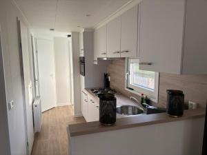 a kitchen with white cabinets and a sink at Chalet Lutafaro near beach Petten in Petten