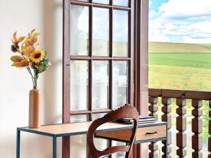 a chair sitting in front of a window with a vase of flowers at Spacious 150 sqm Home in a Natural Setting with Easy Access & Private Courtyard Parking - Balcony, Fire Pit, Ping-Pong, and Relaxing Outdoor Amenities in Gingsheim