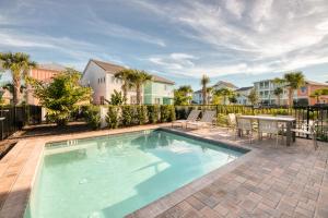 einen Pool mit einem Tisch, Stühlen und Häusern in der Unterkunft Margaritaville Cottages Orlando with H2O Waterpark by Rentyl in Kissimmee