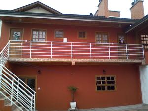 una casa roja con balcón en la parte superior. en Estudio dos Bonecos, en Canela