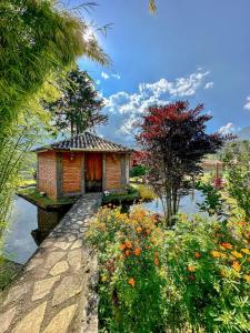 a small house in the middle of a pond with flowers at Pousada Alto da Coruja in Resende