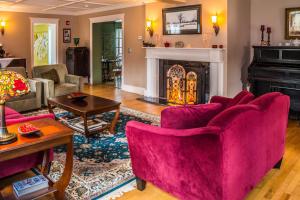 a living room with pink chairs and a fireplace at Cranmore Inn and Suites, a North Conway boutique hotel in North Conway