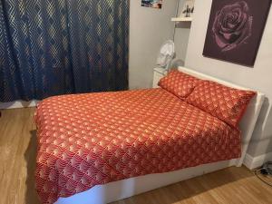 a bed with an orange comforter in a room at A Place to stay in Kettering in Kettering