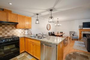 a kitchen with a sink and a stove top oven at 2BR plus den Ski in Ski out Condo with Pool and Hot Tub by Harmony Whistler in Whistler