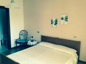 1 dormitorio con 1 cama, 1 silla y 2 fotografías en B&B Andalas, en Olbia