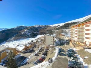 Vue aride d'un hôtel avec des voitures garées dans un parking dans l'établissement T3 Plein Sud - Proche remontées mécaniques, à L'Alpe-d'Huez 15 autres photos