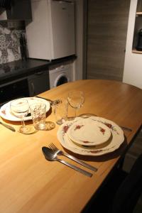 a wooden table with two plates and glasses on it at Studio Malice in Wittelsheim