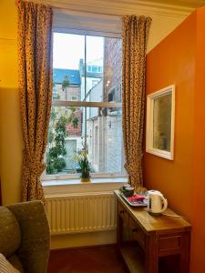 惠特比Bleak House的一个橙色的房间，有一扇窗户，窗边有一张桌子和一张桌子。