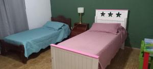 Dos camas en una habitación con paredes verdes. en Departamento Familiar con estacionamiento incluido, en Bahía Blanca