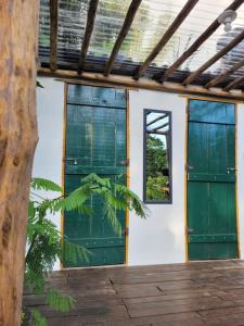 a building with green doors and a window at Nosso Quintal Candeias - Camping in Conceição do Mato Dentro