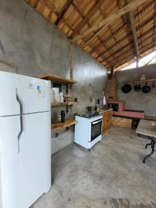 eine Küche mit einem weißen Kühlschrank und einem Tisch in der Unterkunft Nosso Quintal Candeias - Camping in Conceição do Mato Dentro